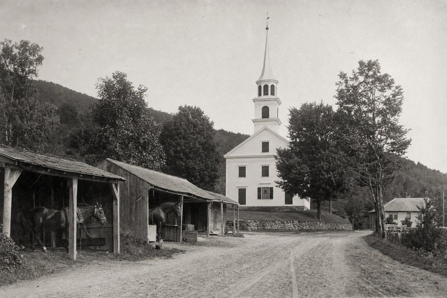 The church with horse sheds along the road about 1890